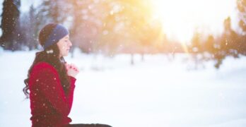 Woman praying in the snow. Forgiveness - Holy and Without Fault