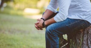 Man with hands folded on his knee in prayer.