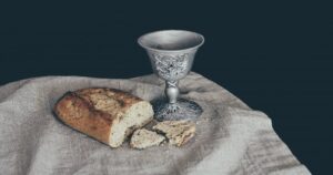 Broken loaf of bread and a wine cup on a cloth. Communion