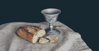 Broken loaf of bread and a wine cup on a cloth. Symbolizing Communion and forbearance with all believers.