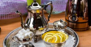 Silver service with tea pot, milk jug, sugar cubes and lemon